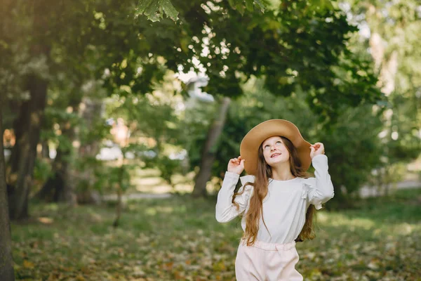 Little girl in a park standing in a park in a brown hat — Stock Photo, Image