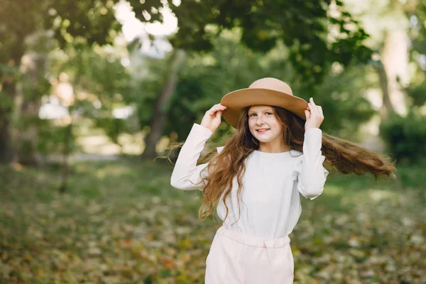 Little girl in a park standing in a park in a brown hat — Stock Photo, Image