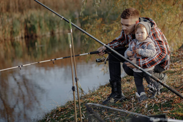 Отец с маленьким сыном у реки на утренней рыбалке
