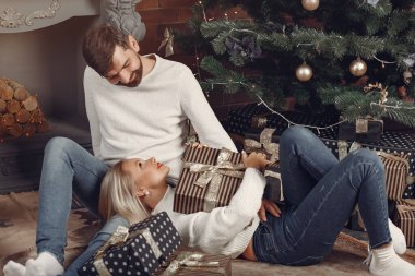 Güzel bir çift Noel ağacının yanında oturuyor.