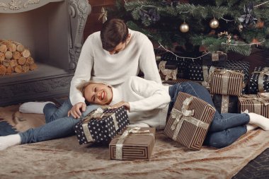 Güzel bir çift Noel ağacının yanında oturuyor.