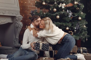 Güzel bir çift Noel ağacının yanında oturuyor.