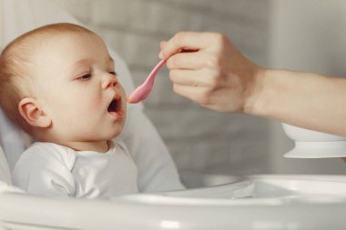 Anne küçük bebeği mutfakta besliyor.