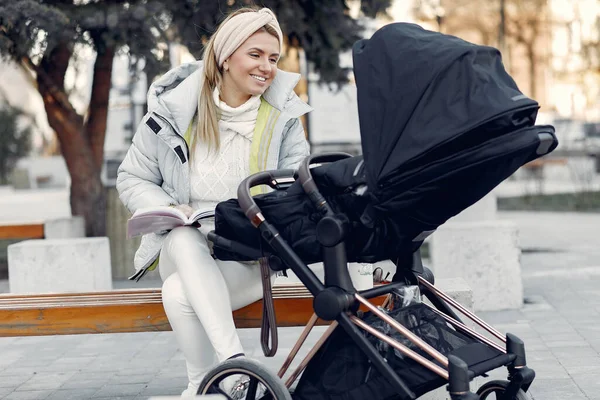 Stylish woman sitting in a city with carriage — Stock Photo, Image