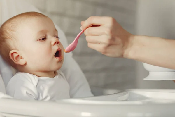 Anne küçük bebeği mutfakta besliyor.