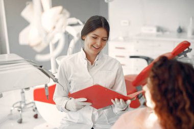 Güzel kız dişçi ofisinde oturuyor.