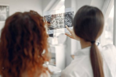 Güzel kız dişçi ofisinde oturuyor.