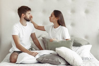 Odada bir yatakta oturan çift.