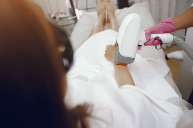 Kozmetoloji stüdyosunda lazer tüy temizleme üzerine çalışan bir kadın.