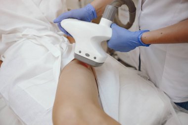 Kozmetoloji stüdyosunda lazer tüy temizleme üzerine çalışan bir kadın.