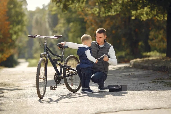 Pai com filho repare a bicicleta em um parque — Fotografia de Stock