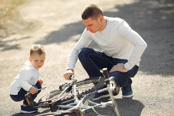 Pai com filho repare a bicicleta em um parque — Fotografia de Stock