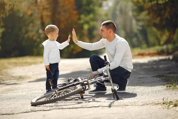 Батько з сином відремонтував велосипед у парку — стокове фото
