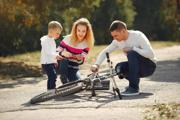 Familia con hijo reparar la bicicleta en un parque —  Fotos de Stock