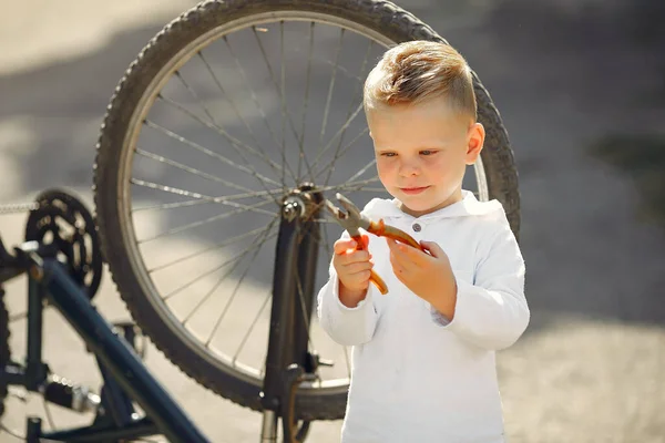 Pequeño niño reparar su bicicleta en un parque —  Fotos de Stock