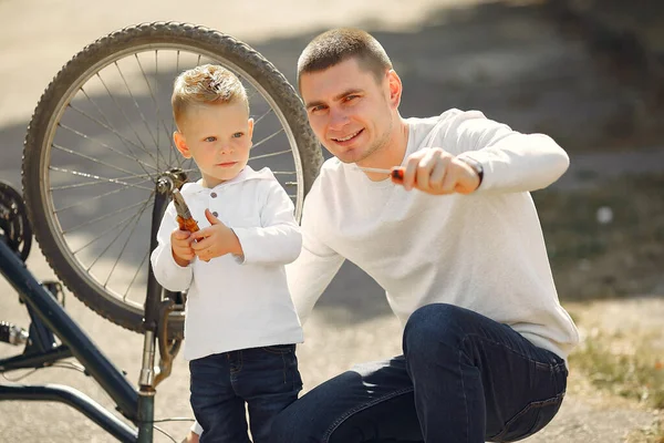 Pai com filho repare a bicicleta em um parque — Fotografia de Stock