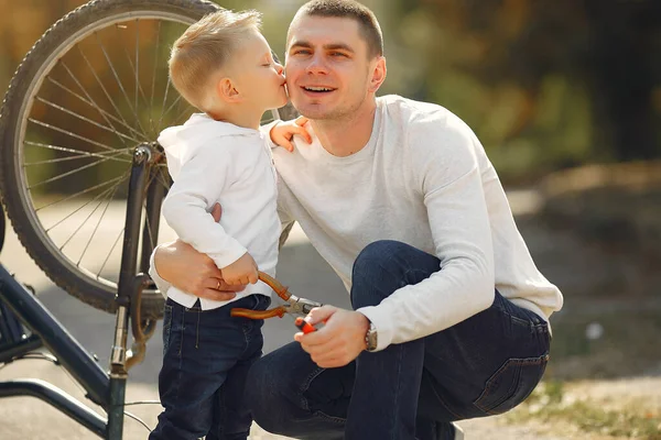 Pai com filho repare a bicicleta em um parque — Fotografia de Stock