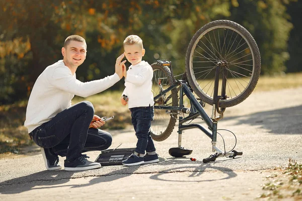 Padre con hijo repare la moto en un parque —  Fotos de Stock