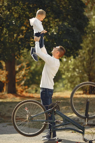 Pai com filho repare a bicicleta em um parque — Fotografia de Stock