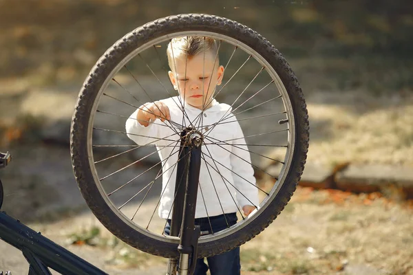 Мальчик чинит велосипед в парке. — стоковое фото