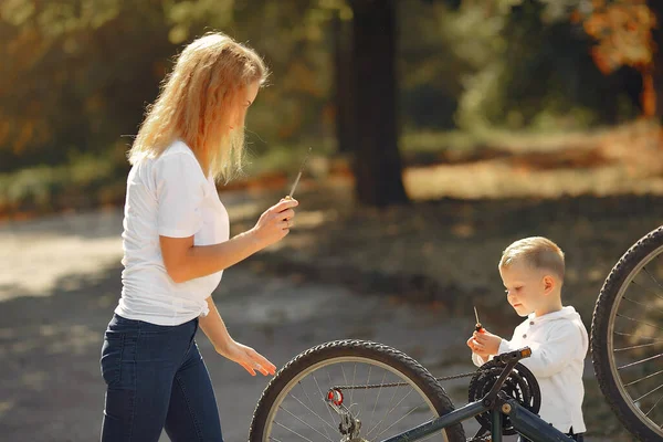 Mãe com filho repare a bicicleta em um parque — Fotografia de Stock