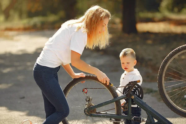 Madre con hijo reparar la bicicleta en un parque —  Fotos de Stock