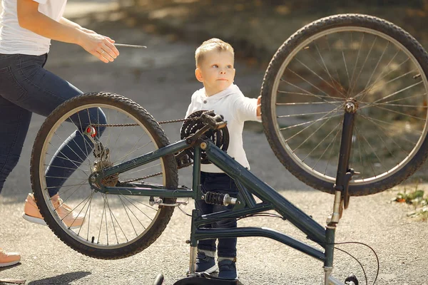 Madre con hijo reparar la bicicleta en un parque —  Fotos de Stock