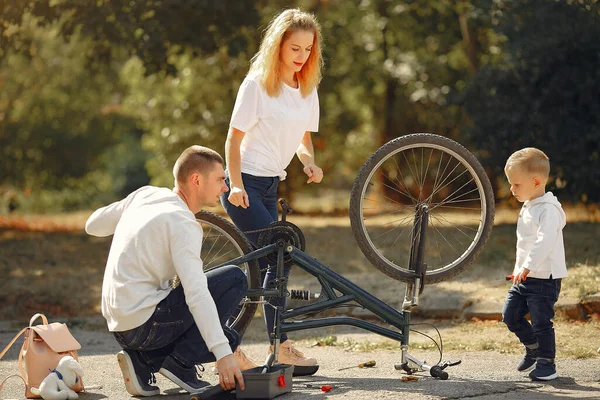 Familia con hijo reparar la bicicleta en un parque —  Fotos de Stock