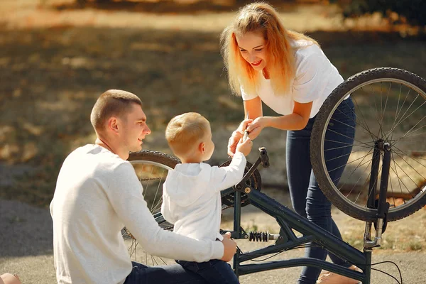 有儿子的家庭在公园里修理自行车 — 图库照片