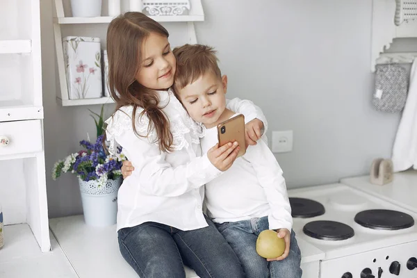 Niños sentados en una cocina en casa — Foto de Stock