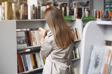 Öğrenci kütüphanede kitap arıyor.