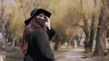 Siyahlı güzel kız parkta maske takıyor.