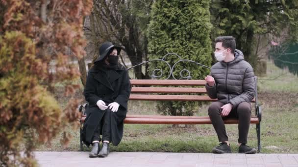 Леді і молодий чоловік сидять на кінцях бенкету в парку — стокове відео