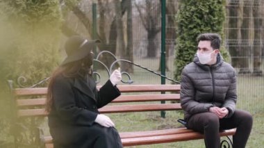 Bayan ve genç adam bir bankın ucunda oturuyorlar.