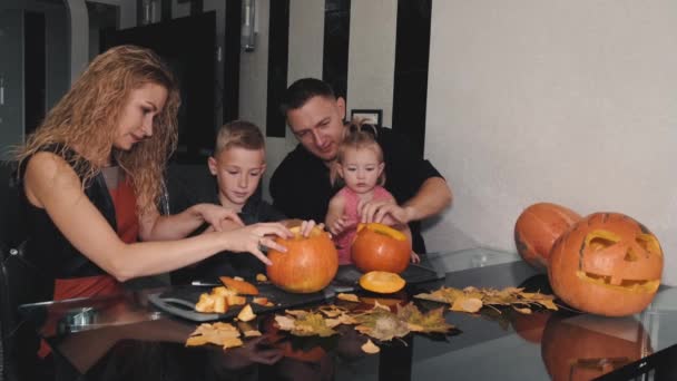 家族全員が家でテーブルの上でハロウィンのためにカボチャを彫る — ストック動画