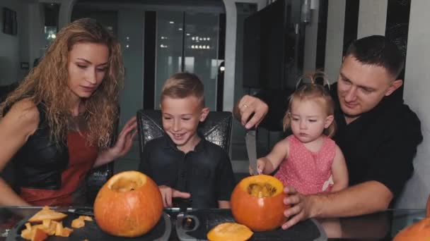 Família inteira esculpe abóboras para halloween na mesa em casa — Vídeo de Stock