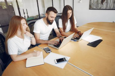 Genç ekip birlikte çalışıyor ve bilgisayarı kullanıyor.