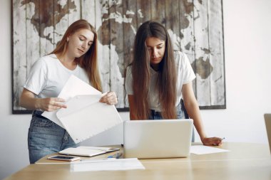 Ofiste çalışan beyaz tişörtlü iki kız.