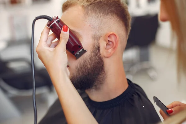 Woma shaving mans beard in a barbershop