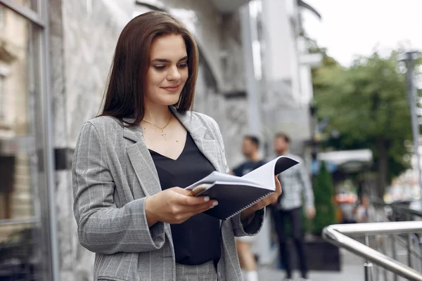Elegante zakenvrouw die in een stad werkt en het notitieboekje gebruikt — Stockfoto