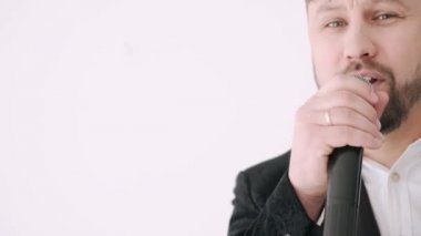 Elinde mikrofon tutan ve şarkı söyleyen takım elbiseli bir adamın portresi.