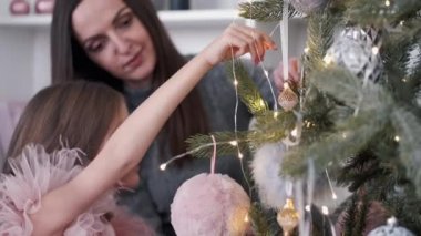 Anne ve kızı evde birlikte Noel ağacı süslüyorlar.