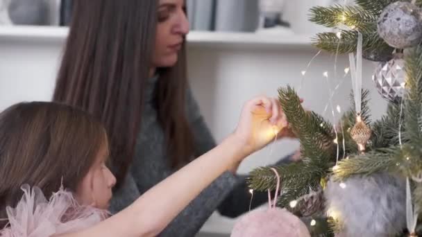 母と娘が一緒に家でクリスマスツリーを飾る — ストック動画