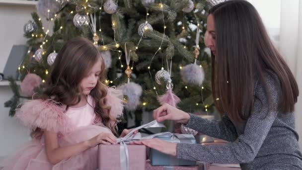 Madre e hija en vestidos desempacando cristmas regalos en casa — Vídeos de Stock