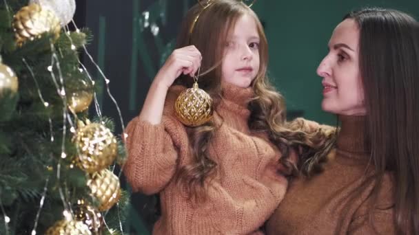 Portrét dívky držící výzdobu s matkou v blízkosti cristmas stromu — Stock video