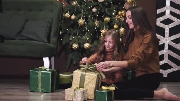 어머니와 어린 딸 이 바닥에 앉아 선물을 풀고 있다 — 비디오