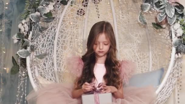 Klein meisje zittend in versierde studio en met geschenk — Stockvideo