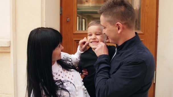 Mother and father are holding their son in hands and playing with his face — Stock Video