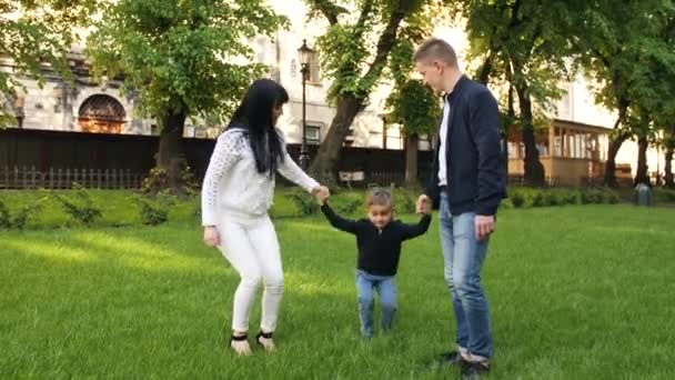 Anne ve baba çimlerin üzerinde oğluyla eğleniyorlar. — Stok video