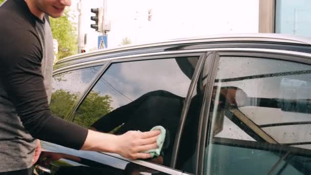 Чоловік прибирає вікна автомобіля килимком у точці автомийки — стокове відео